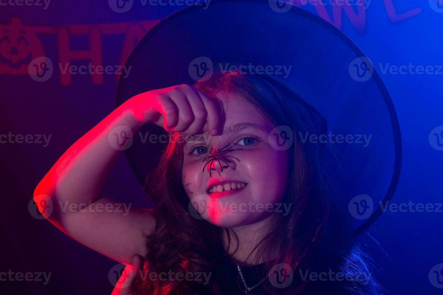 Funny child girl in witch costume for Halloween with spider. photo