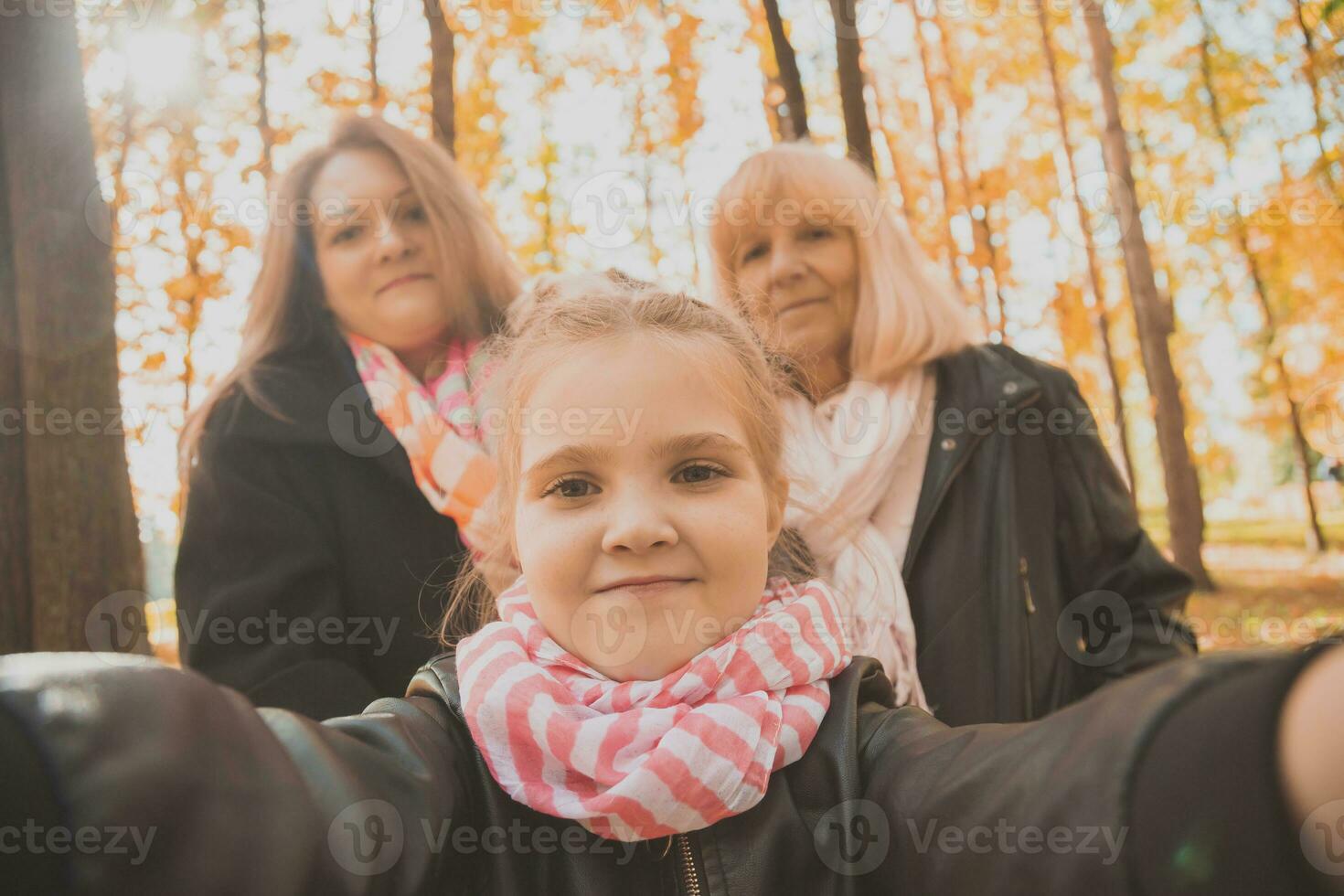 Three generations of women and dog feel fun look at camera posing for self-portrait picture together, funny excited child, mom and grandmother have fun enjoy weekend take selfie on gadget in autumn photo