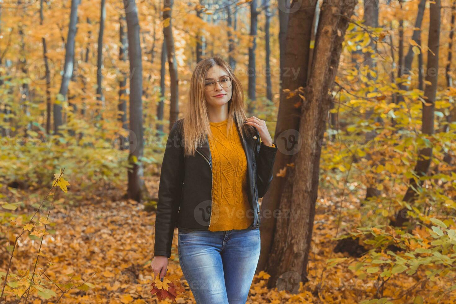 Cute smiley woman holding autumn leaves in fall park. Seasonal, lifestyle and leisure concept. photo