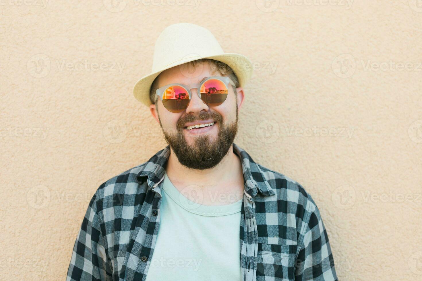 Portrait handsome man wearing summer hat and plaid shirt smiling happy near wall - travel vacations and summer holiday concept photo