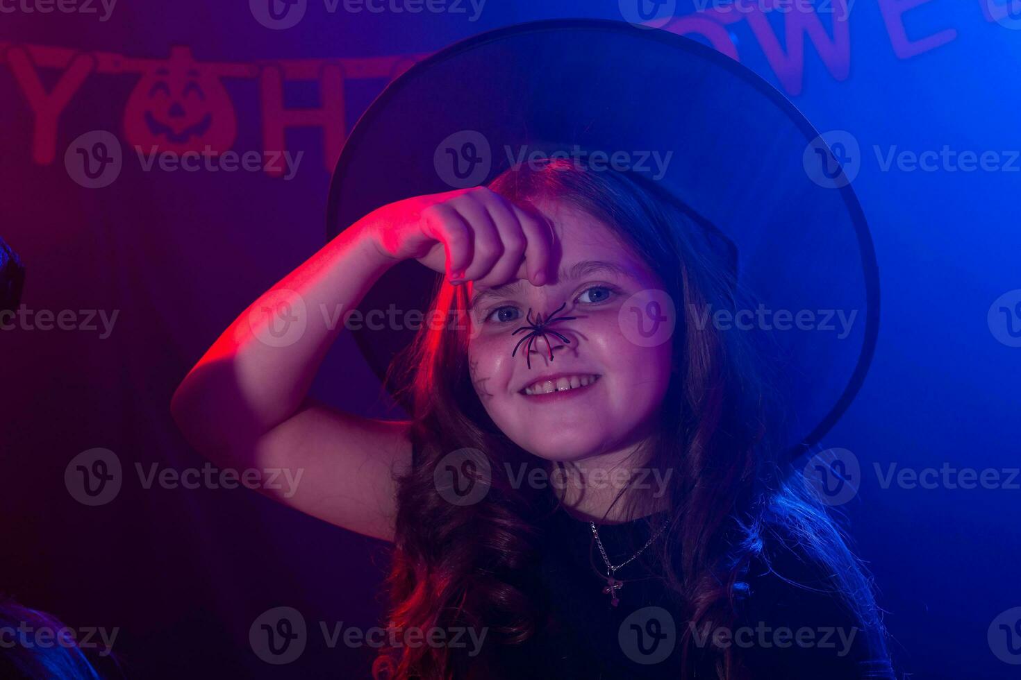 Funny child girl in witch costume for Halloween with spider. photo