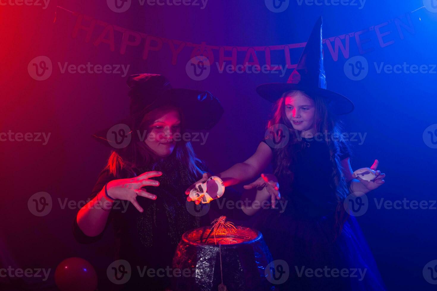 Two halloween witches making a potion and conjure in halloween night. Magic, holidays and mystic concept. photo