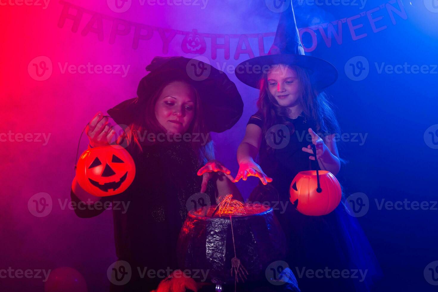 Two halloween witches making a potion and conjure in halloween night. Magic, holidays and mystic concept. photo