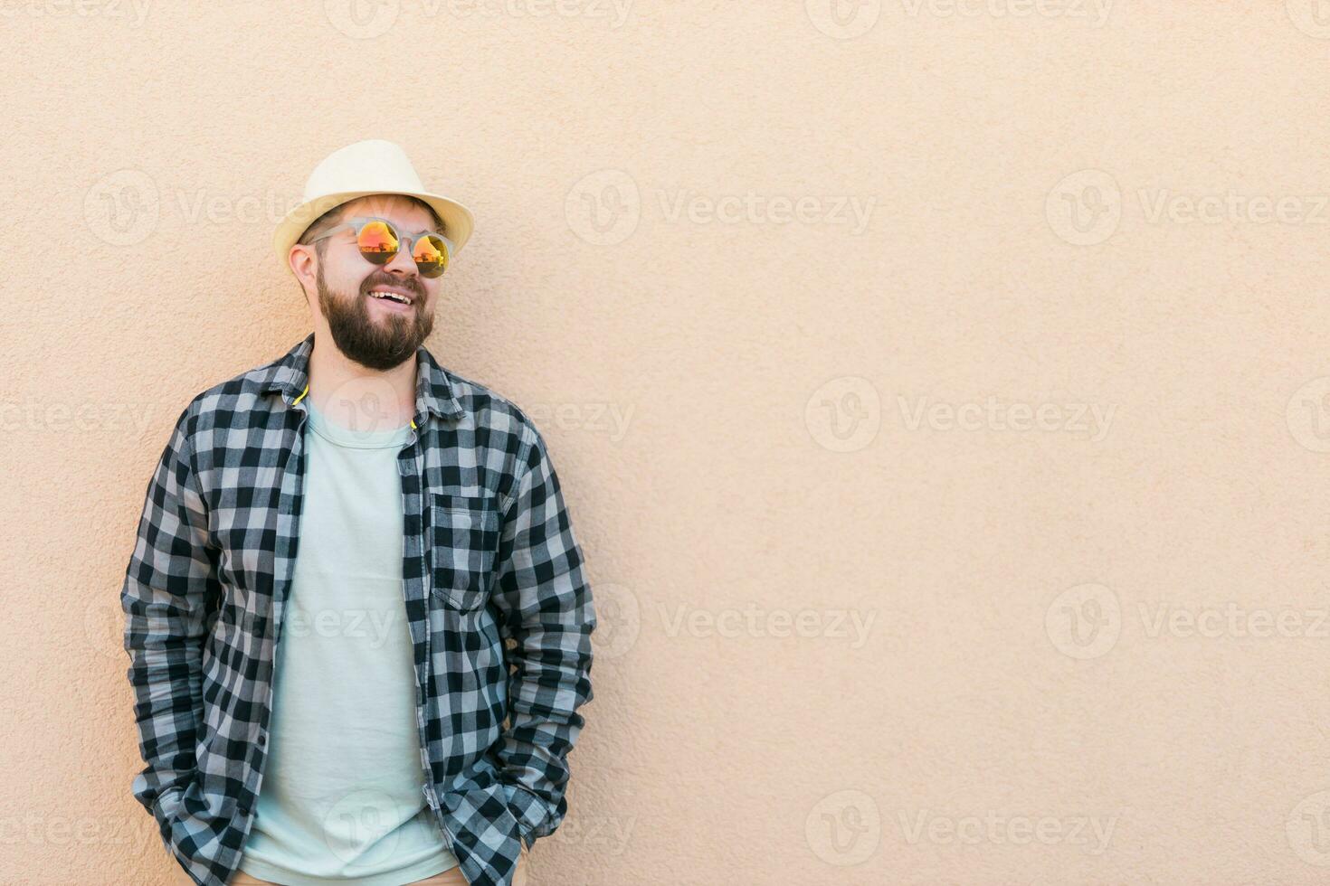 Bearded man in summer clothes and hat stand over beige wall on street city urban and travel concept - copy space and empty space for advertising photo