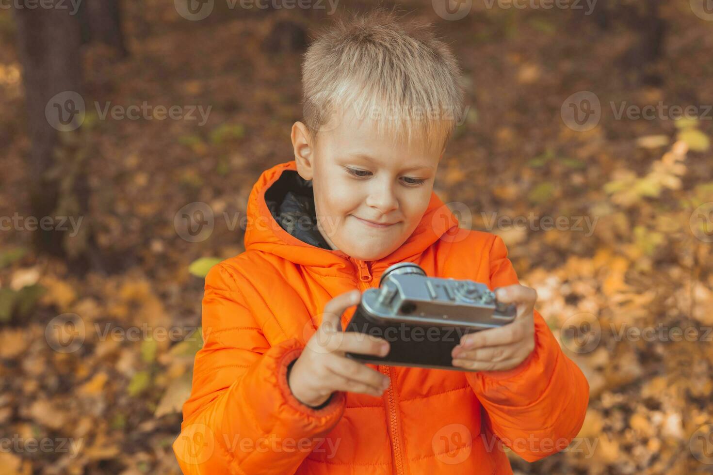 Boy with retro camera taking pictures outdoor in autumn nature. Leisure and photographers concept photo