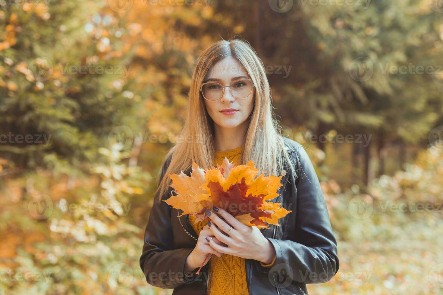Cute smiley woman holding autumn leaves in fall park. Seasonal, lifestyle and leisure concept. photo