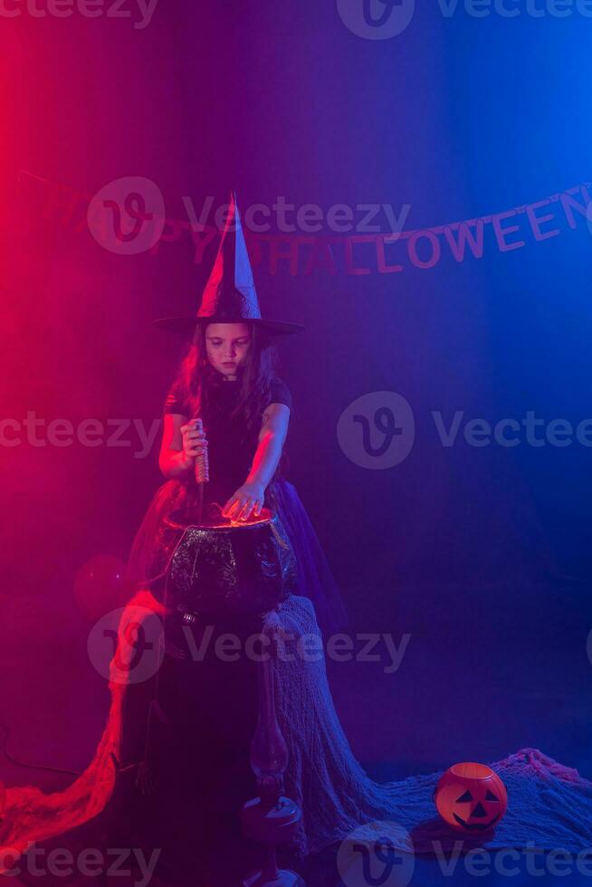 Little witch child cooking potion in the cauldron on Halloween. photo