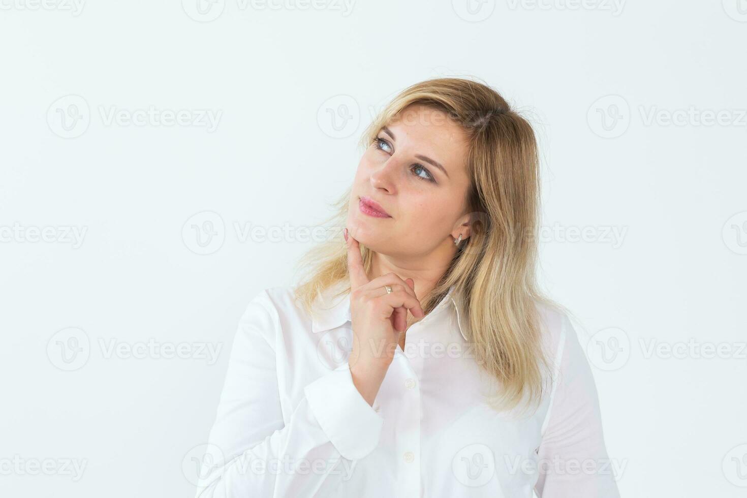 bonito retrato de joven hermosa mujer pensando mirando izquierda y sonriente un poco teniendo un dedo a barbilla aislado en blanco antecedentes foto