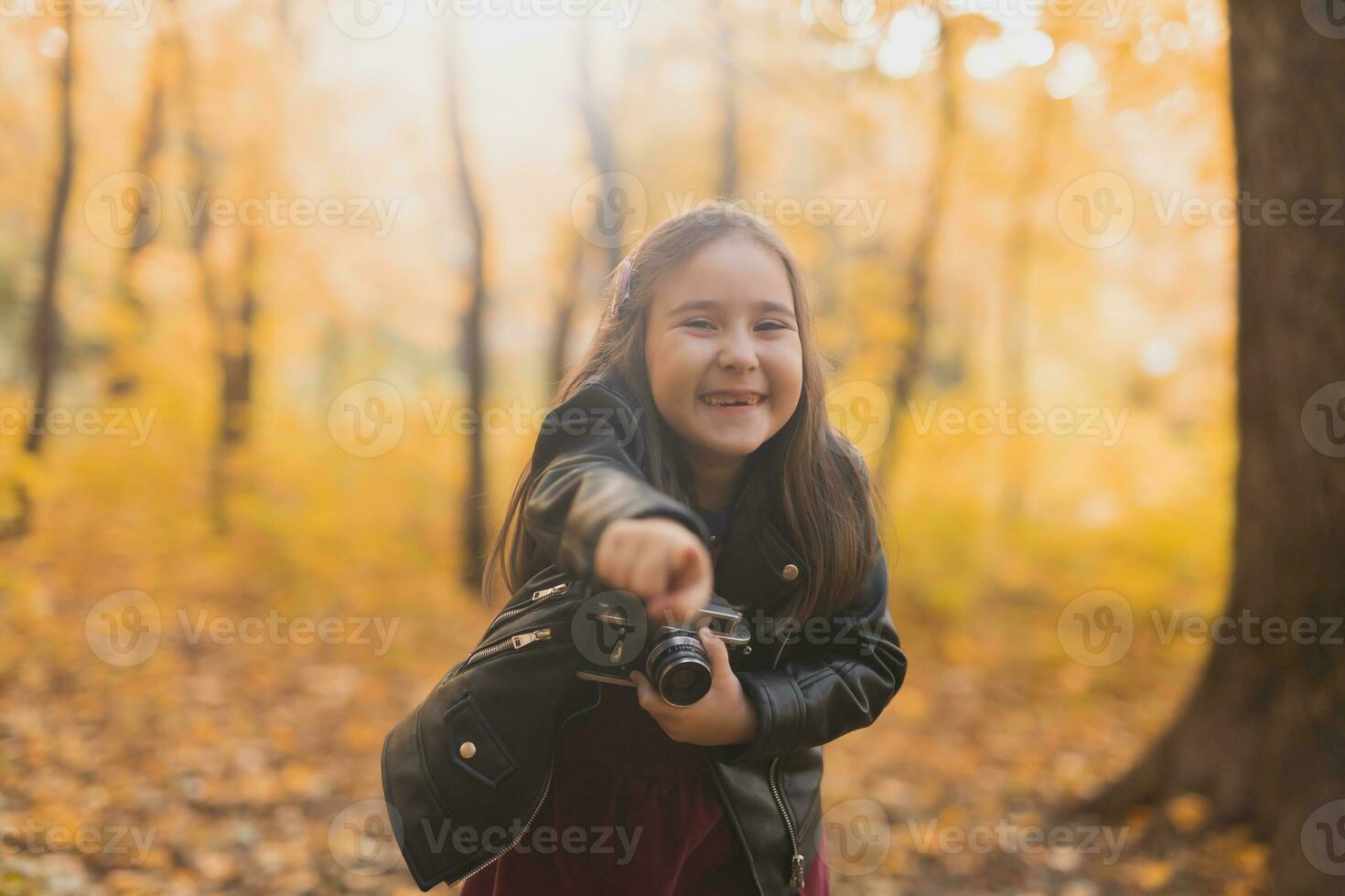 A little girl take a photo with old retro camera in autumn nature. Leisure and hobby concept.