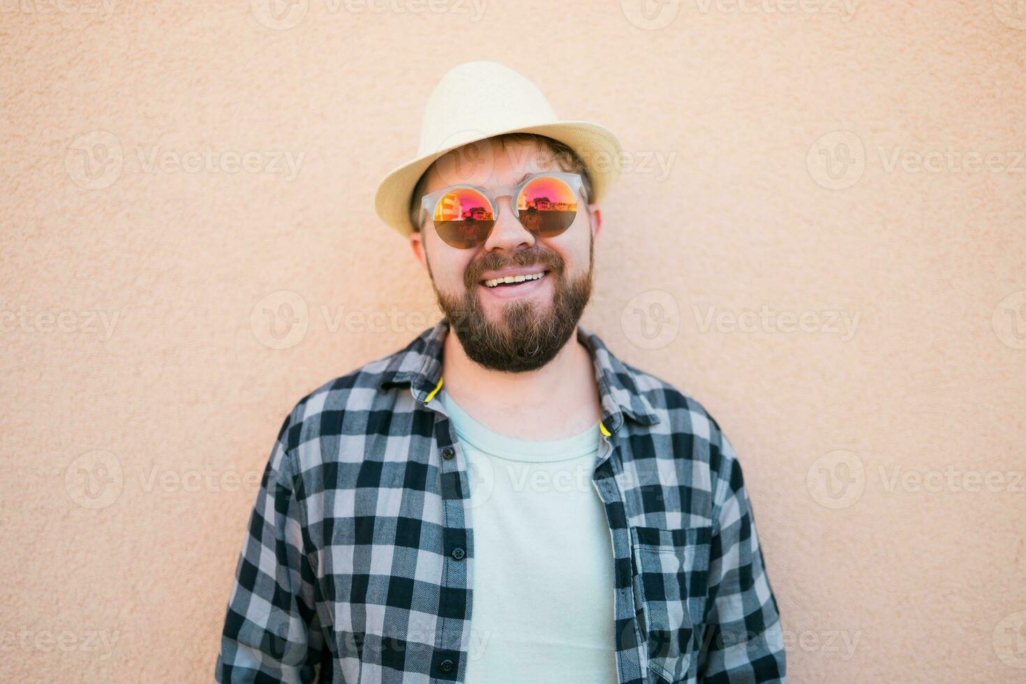 Bearded man portrait in summer clothes and hat stand over beige wall on street city urban and travel concept photo