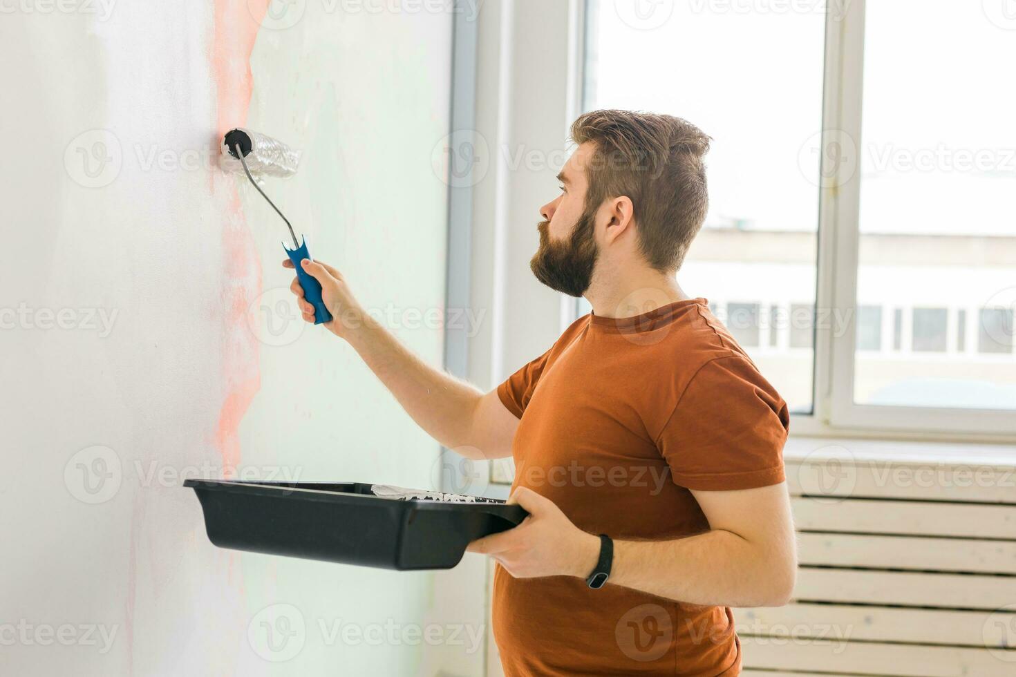 Man painting wall with paint roller - renovation and redecoration concept photo