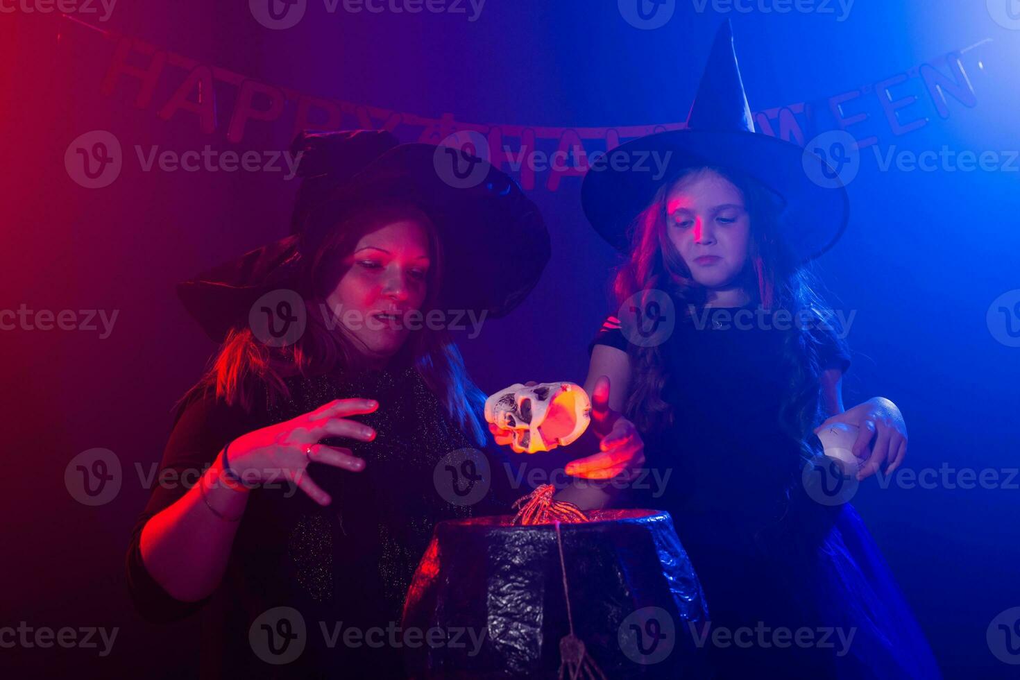 Two halloween witches making a potion and conjure in halloween night. Magic, holidays and mystic concept. photo