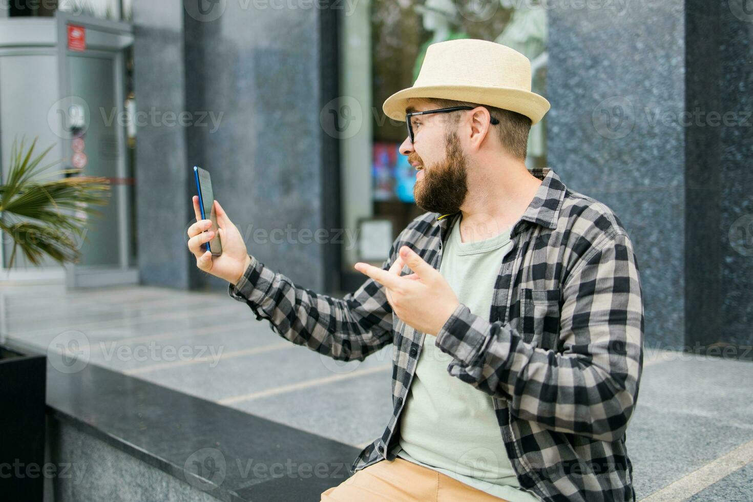 Bearded man doing video call on smartphone outdoor - video connection and technologies concept photo