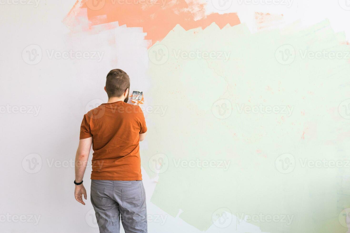 Young man using spatula and plastering of wall with white fresh finishing putty. Closeup. Repair work of home. Empty place for text. Side view. photo