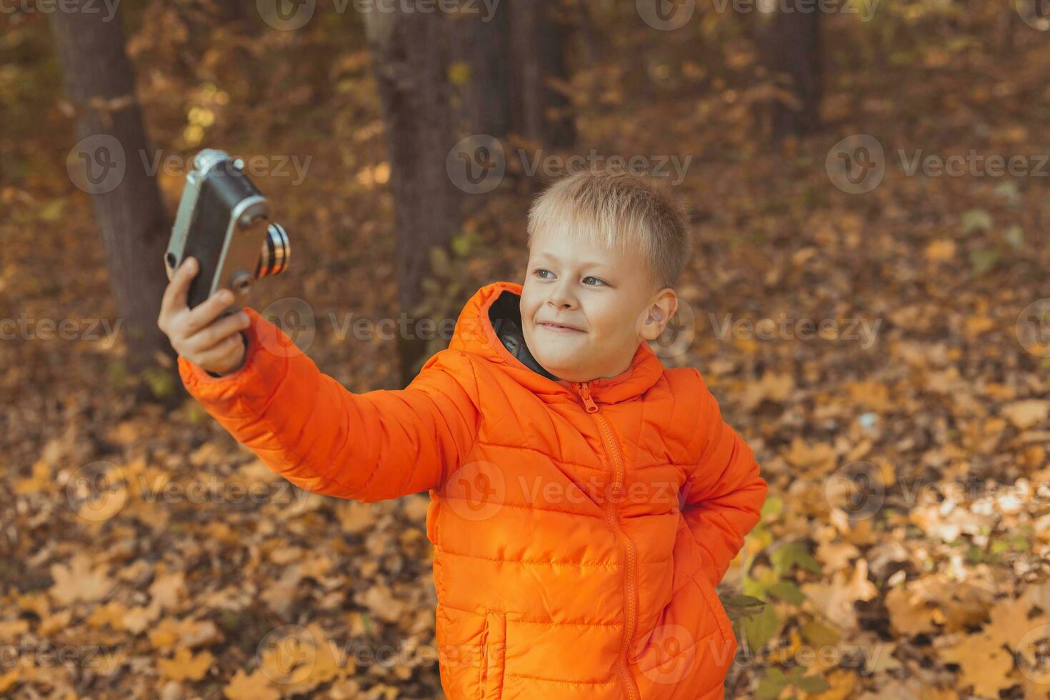 Boy in park in autumn taking selfie photo. Fall and leisure concept. photo