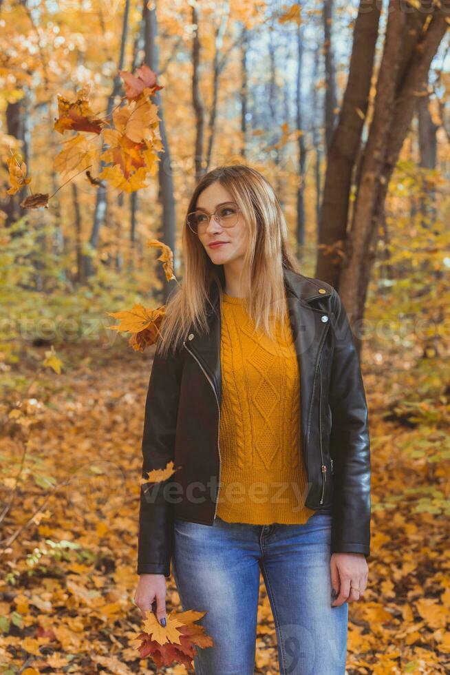 niña sostiene caído hojas y camina en otoño parque. estacional concepto. foto