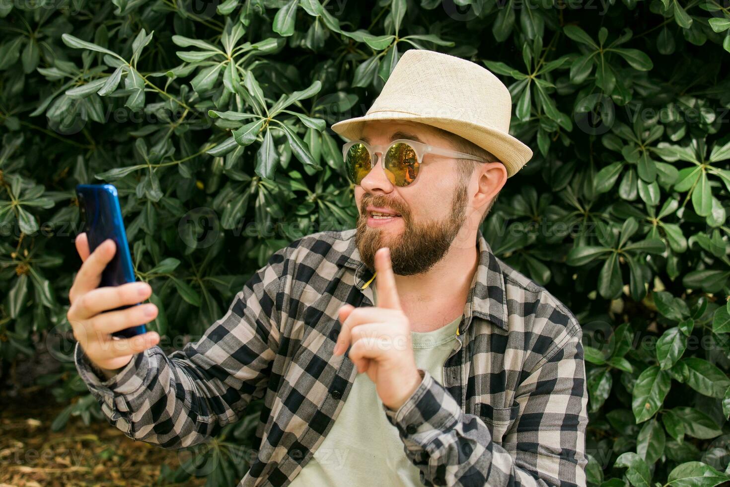 Bearded man doing video call on smartphone outdoor - video connection and technologies concept photo