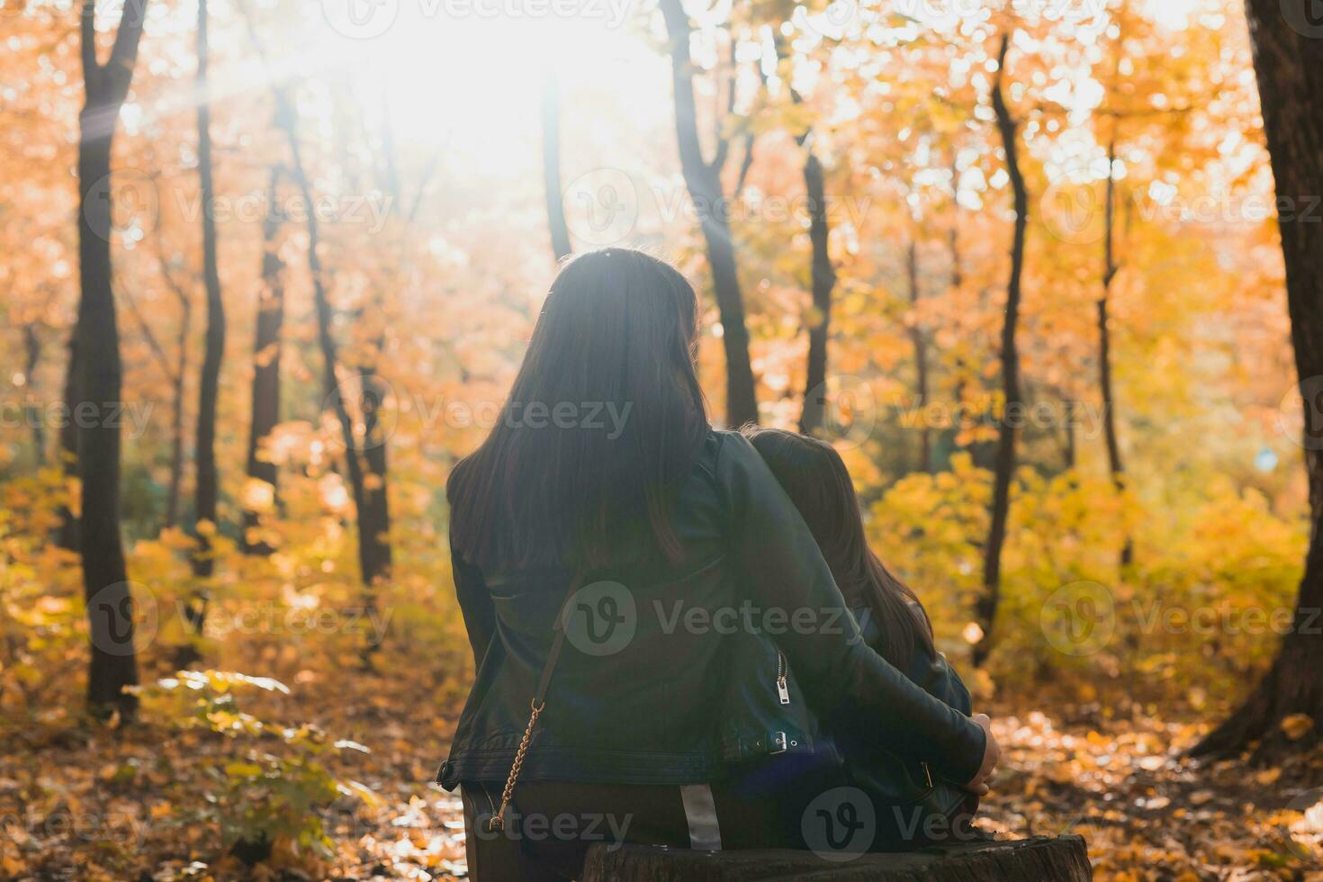 madre con su hija sentado en un tocón en otoño parque. soltero padre y temporada concepto. foto