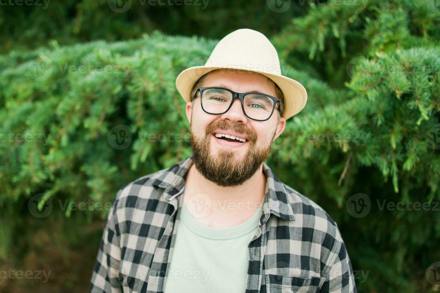 riendo atractivo hombre vistiendo sombrero terminado verde árbol antecedentes - emoción y vacaciones viaje Días festivos concepto foto