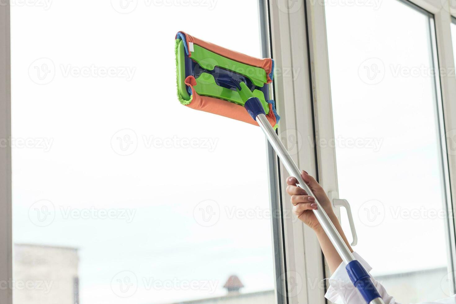 Happy woman cleaning window with sponge mop at home - housework and housekeeping concept photo