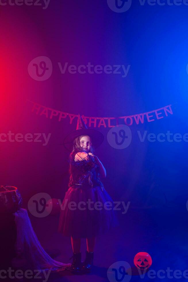 Little girl holds broom on Halloween holiday. Kid girl wear witch costume. Fantasy, fairy tale and masquerade concept. photo