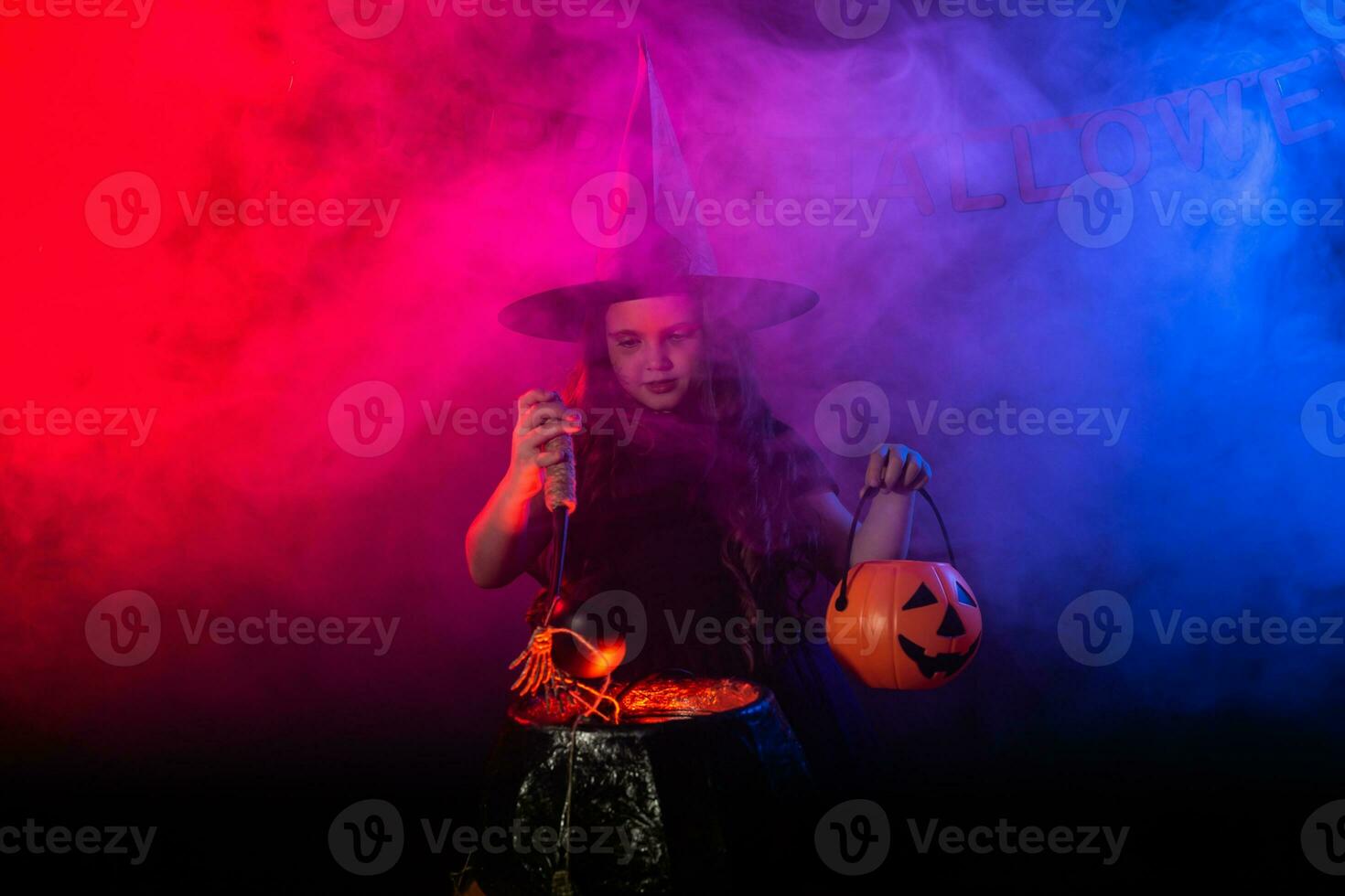 Little witch child cooking potion in the cauldron on Halloween. photo