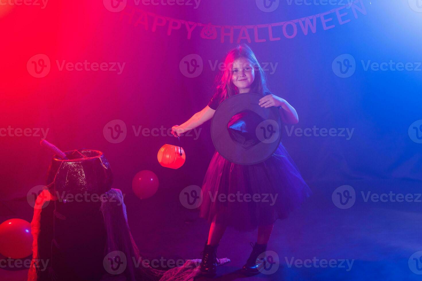 pequeño niña sostiene calabaza Jack en Víspera de Todos los Santos día festivo. niño niña vestir bruja traje. fantasía, hada cuento y mascarada concepto. foto