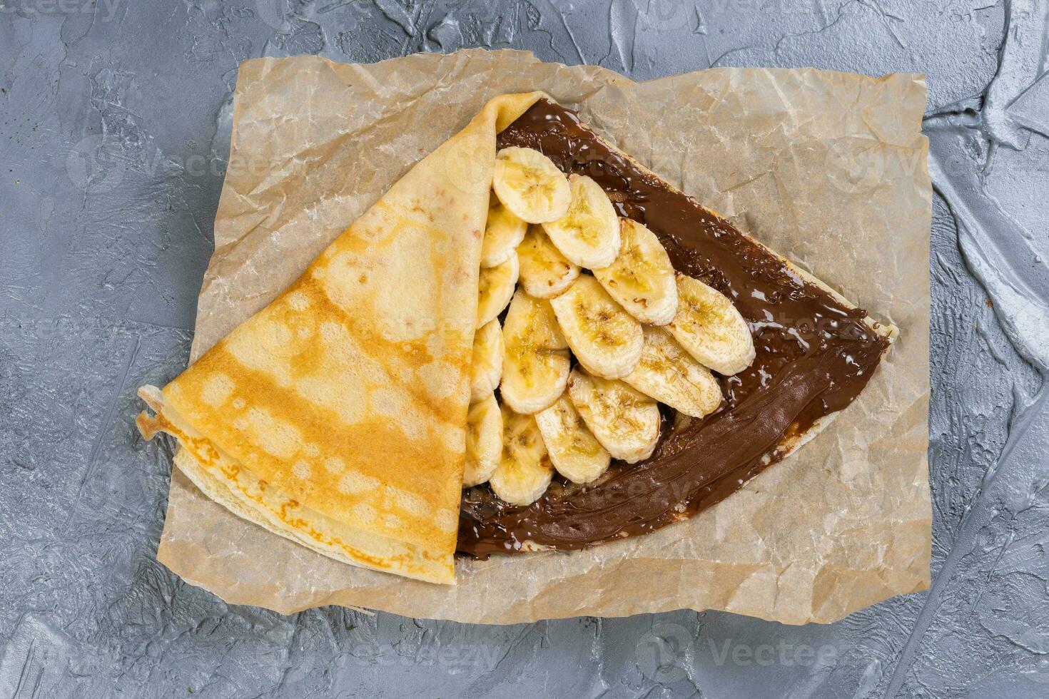 Crepes stuffed with chocolate spread and banana. Thin pancakes. Sweet dessert. French cuisine top view photo