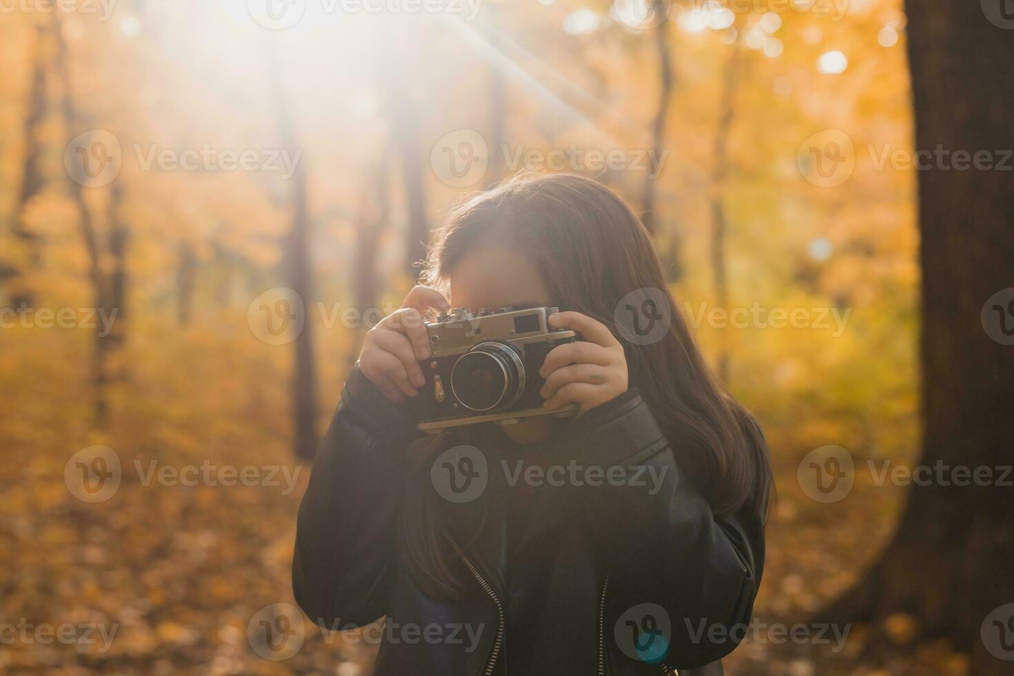 Child girl using an old-fashioned camera in autumn nature. Photographer, fall season and leisure concept. photo