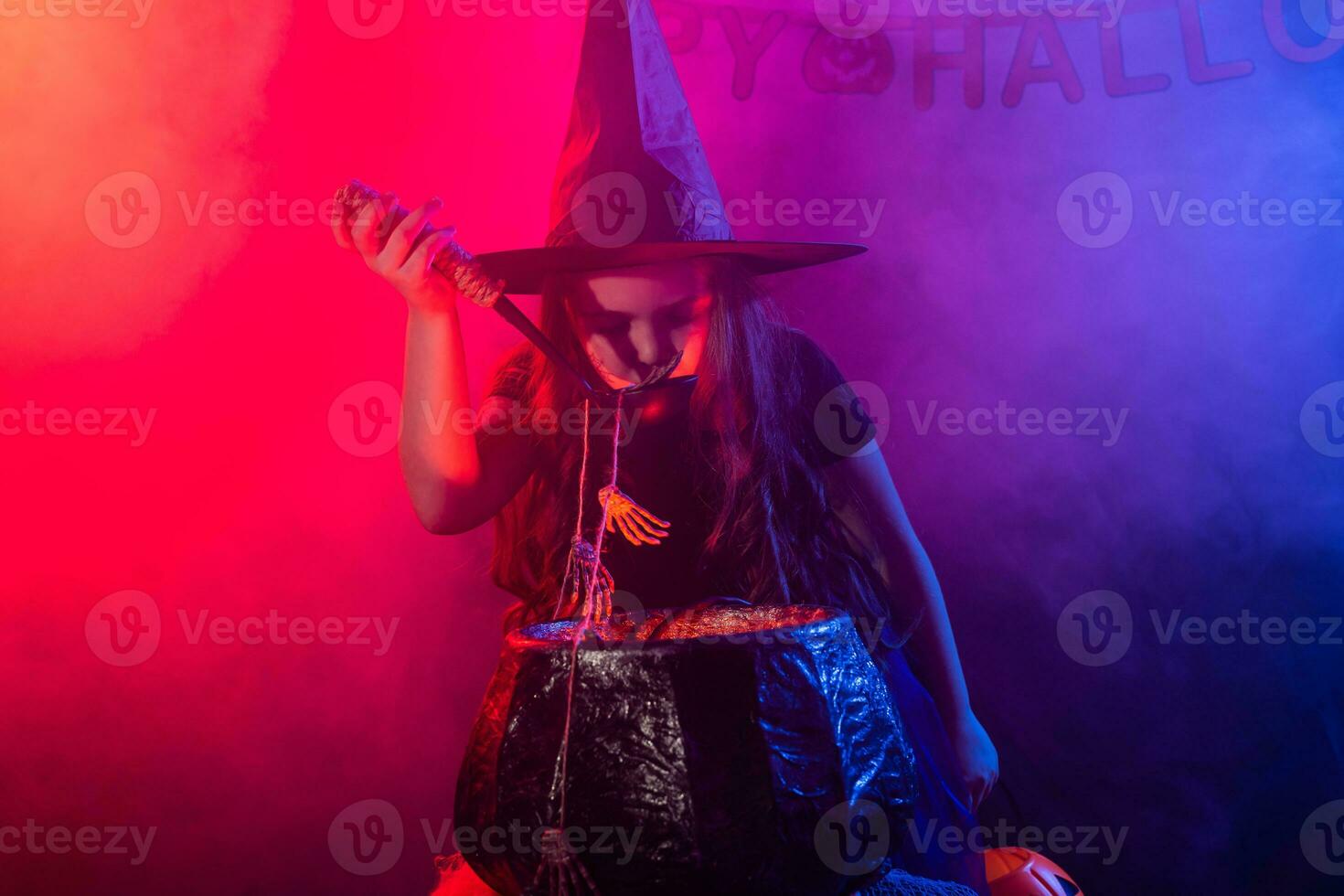 Little witch child cooking potion in the cauldron on Halloween. photo