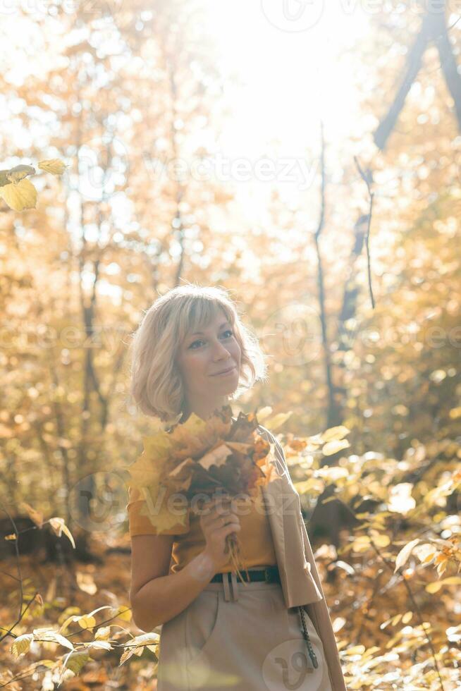 Portrait of beautiful young woman walking outdoors in autumn. Fall season and stylish girl concept. photo