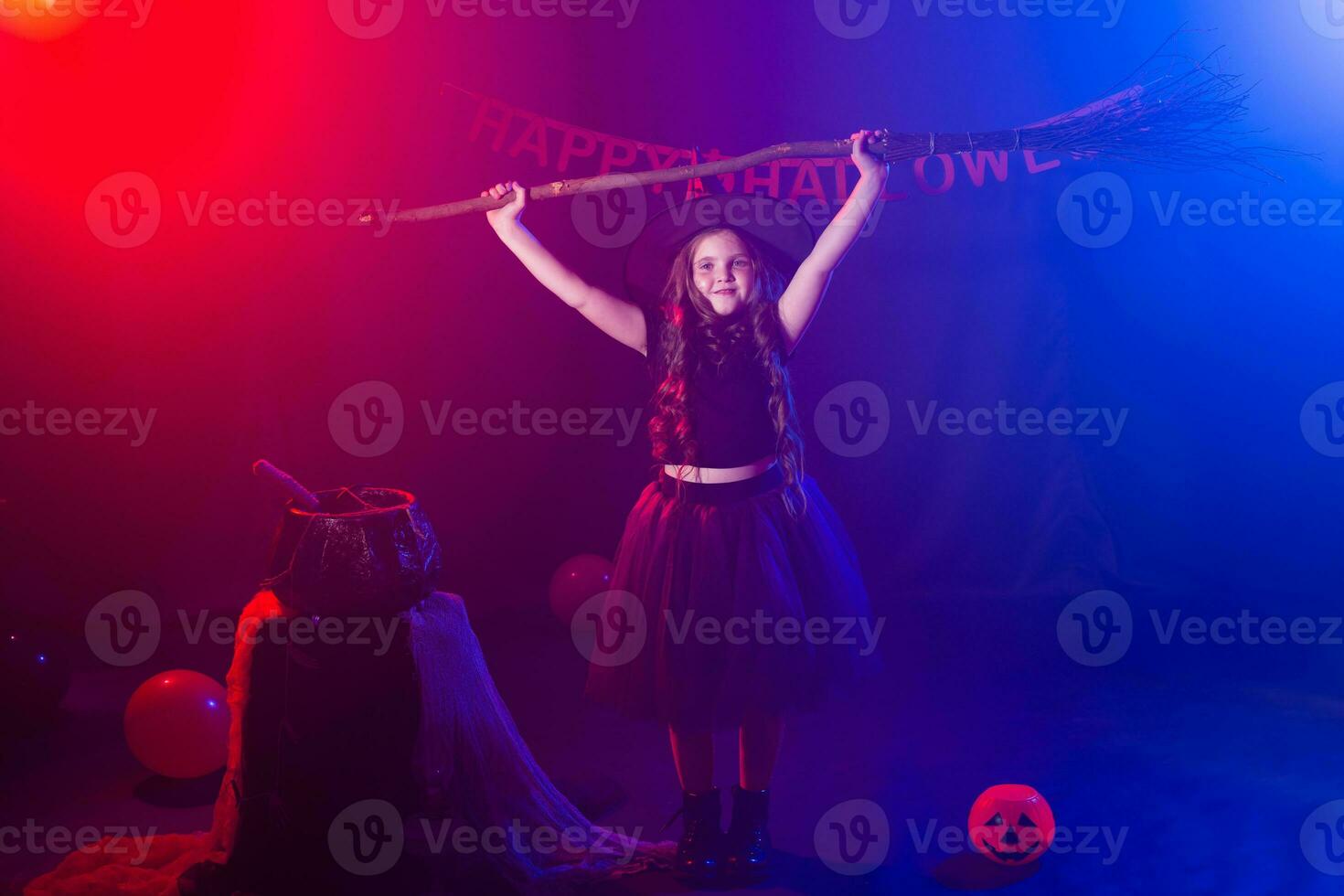 Funny child girl in witch costume for Halloween with pumpkin Jack and broom. photo