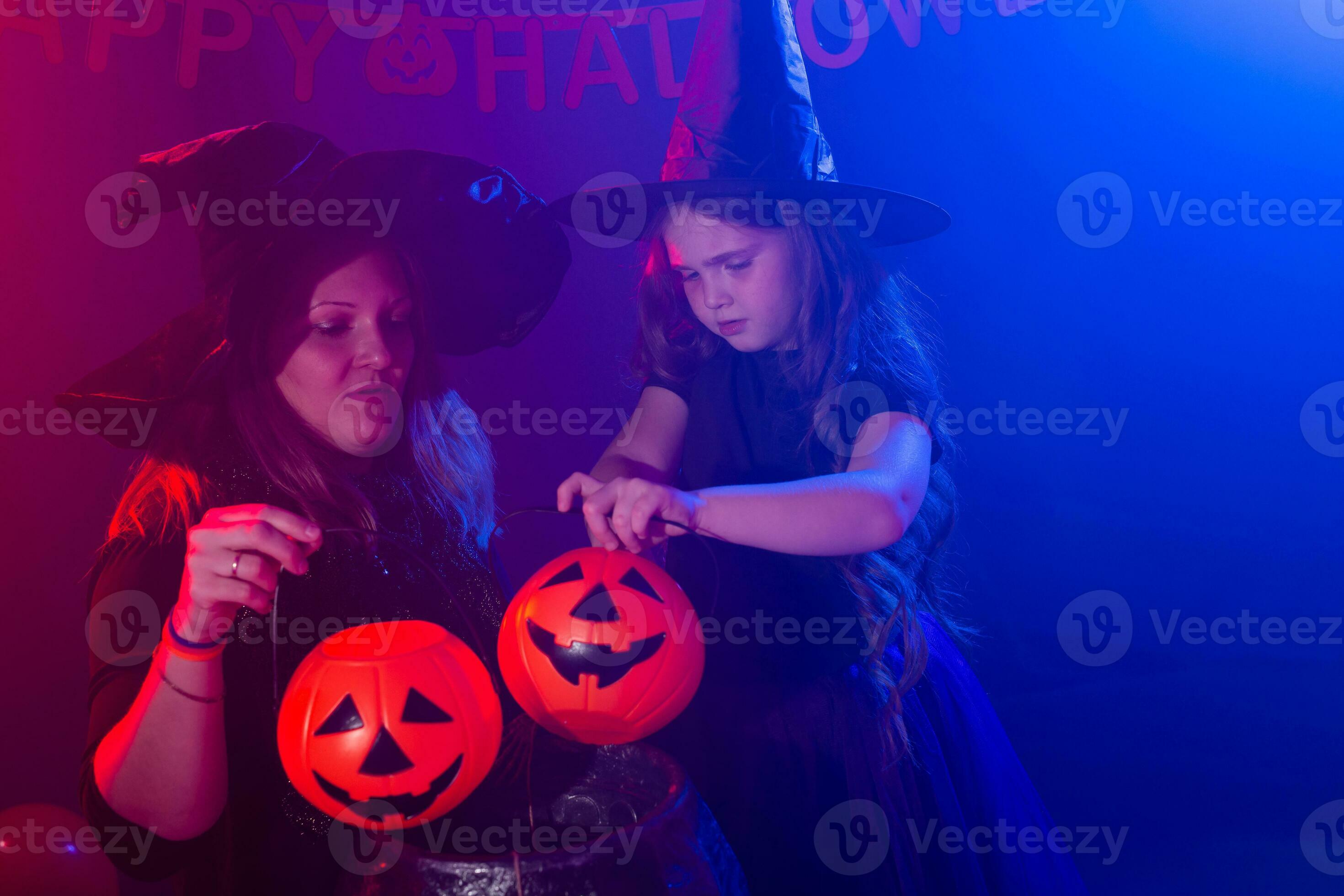 Funny child girl and woman in witches costumes for Halloween making