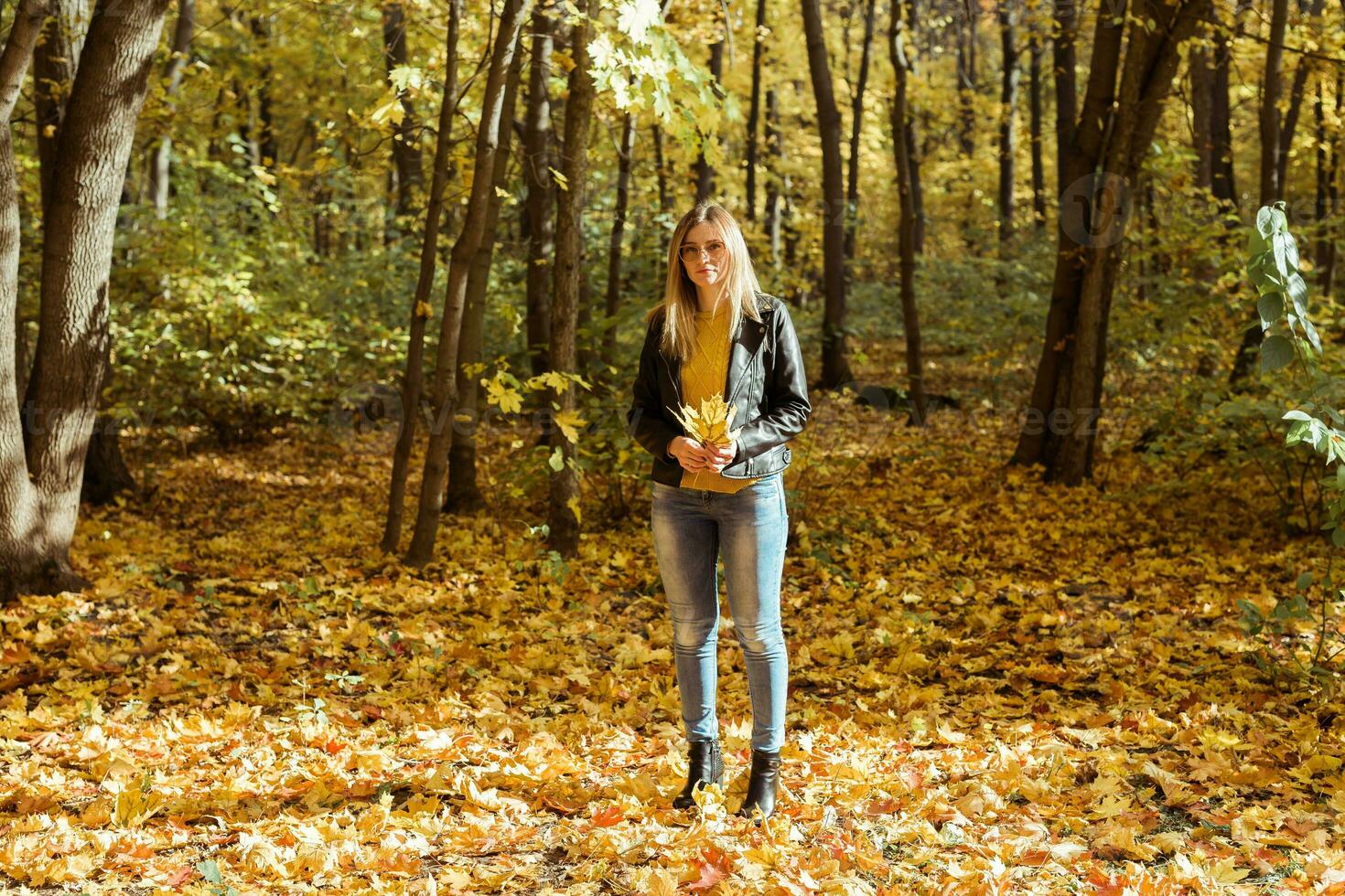 Portrait of beautiful woman holds autumn leaves. Stylish youth and fall season concept. photo