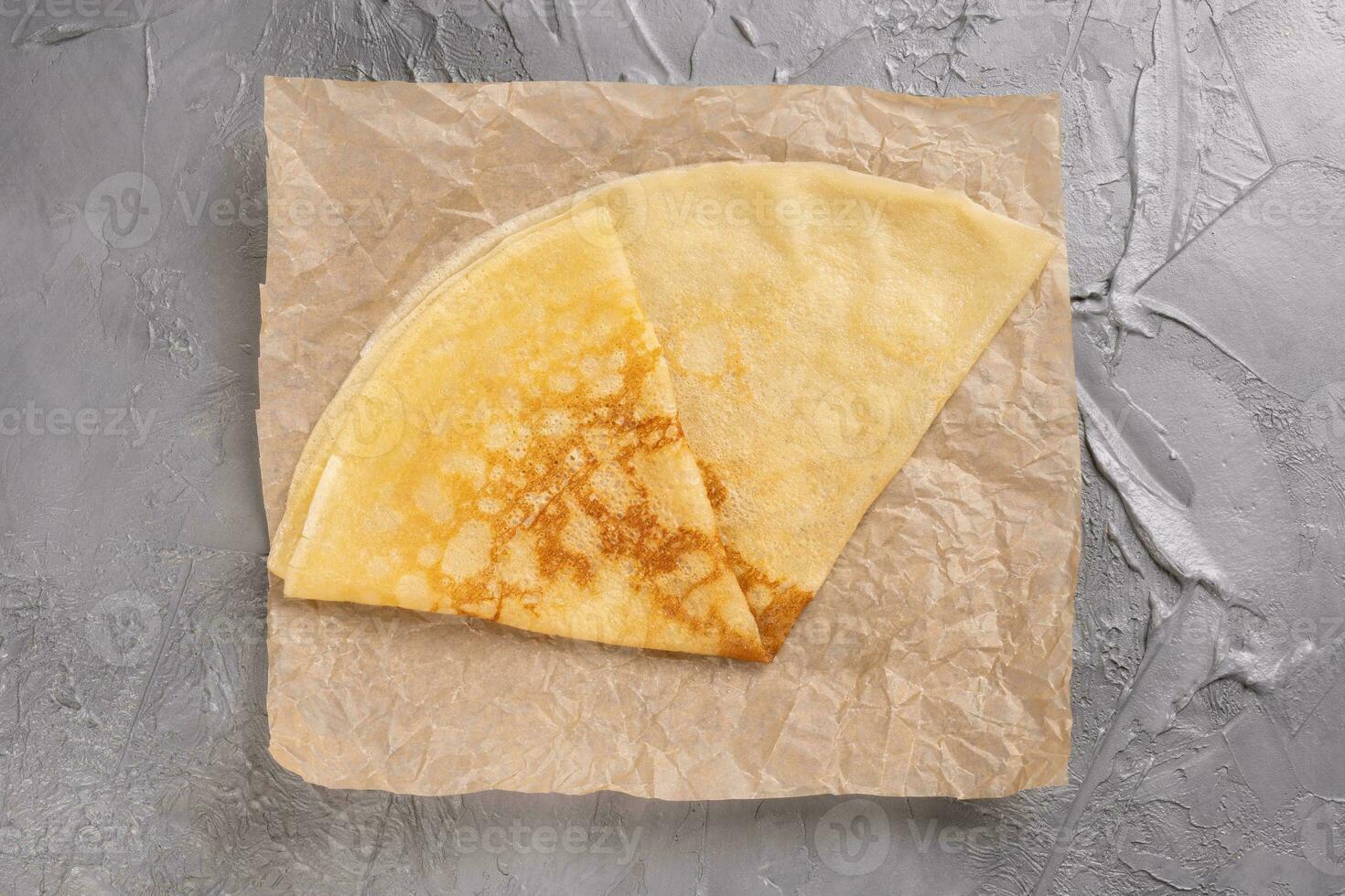 Plain pancake and baking paper background top view. photo