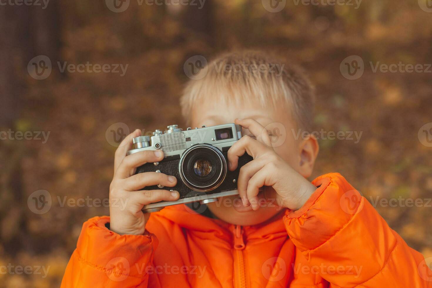 Boy with retro camera taking pictures outdoor in autumn nature. Leisure and photographers concept photo