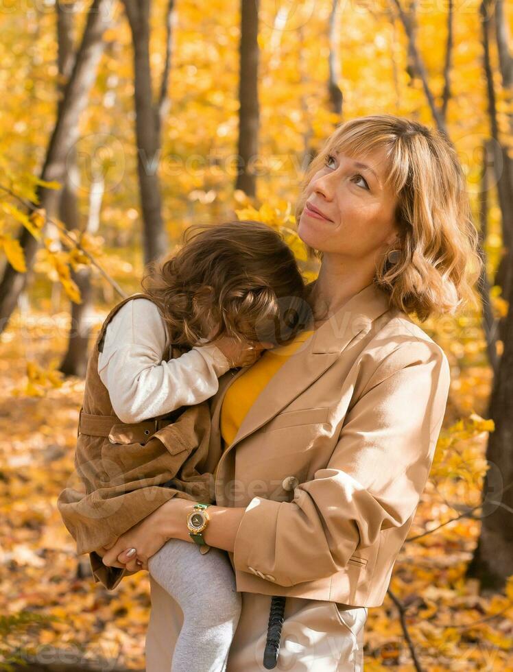 Mother comforting her crying little girl in autumn nature. Emotions and family concept. photo