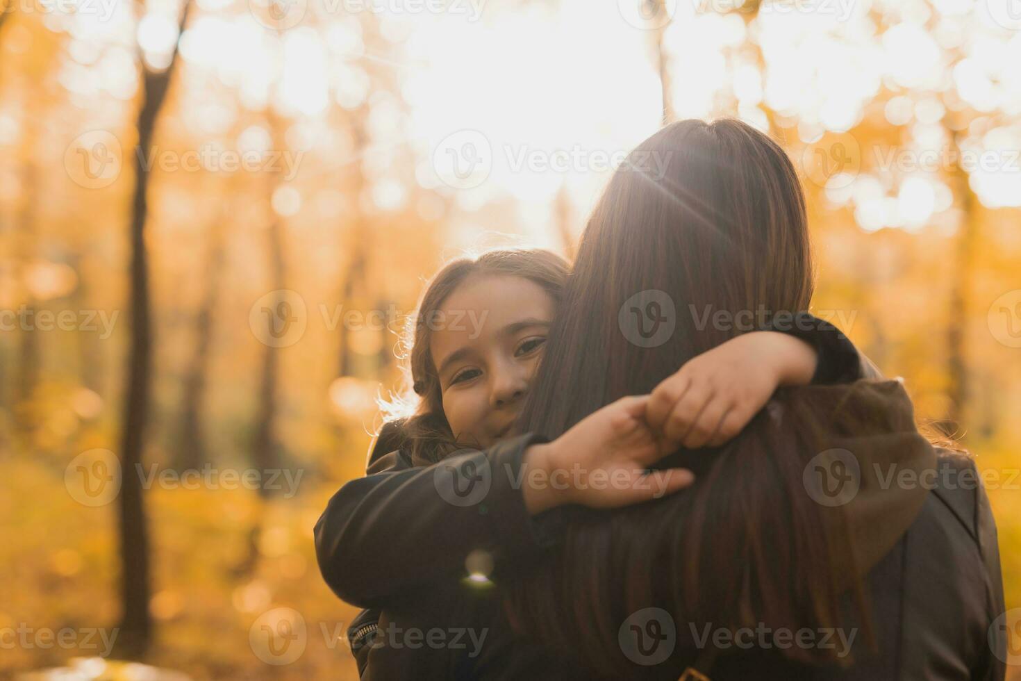 Mother and daughter spend time together in autumn yellow park. Season and single parent concept. photo