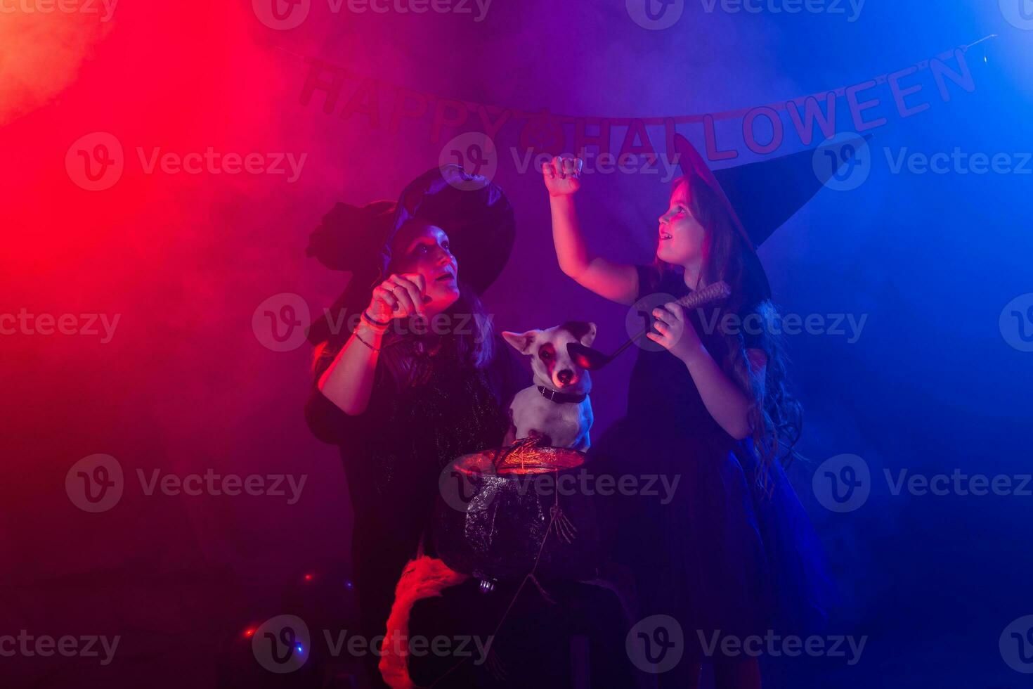Funny child girl and woman in witches costumes for Halloween with dog. photo