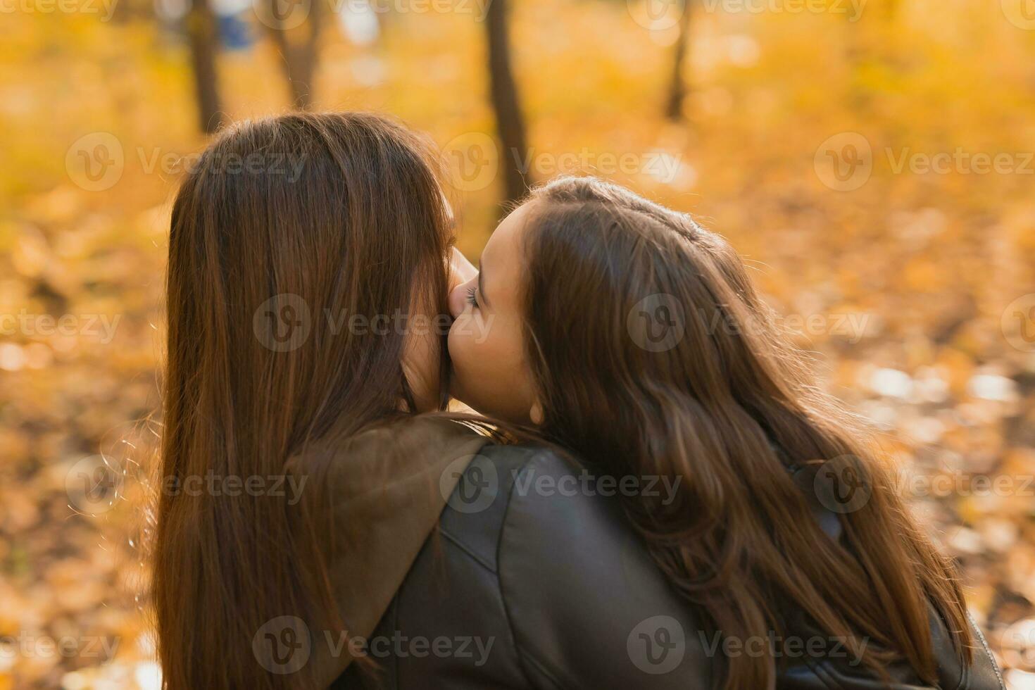 Mother and daughter spend time together in autumn yellow park. Season and single parent concept. photo