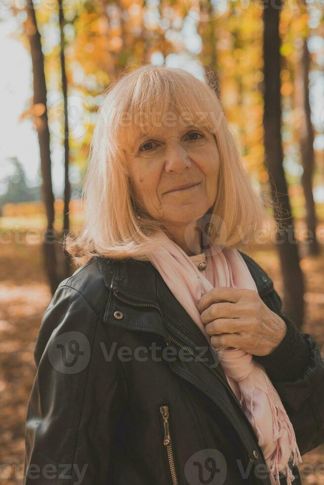 mayor mujer disfrutando otoño en parque. activo envejecimiento y mayor hembra concepto. foto