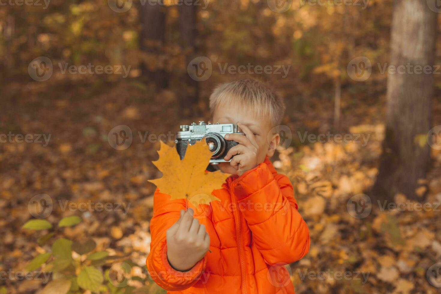 Boy with retro camera taking pictures outdoor in autumn nature. Leisure and photographers concept photo