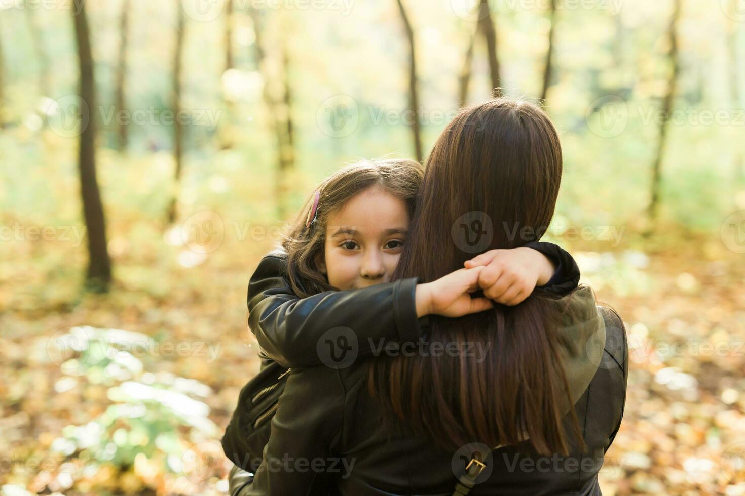 Mother and daughter spend time together in autumn yellow park. Season and single parent concept. photo