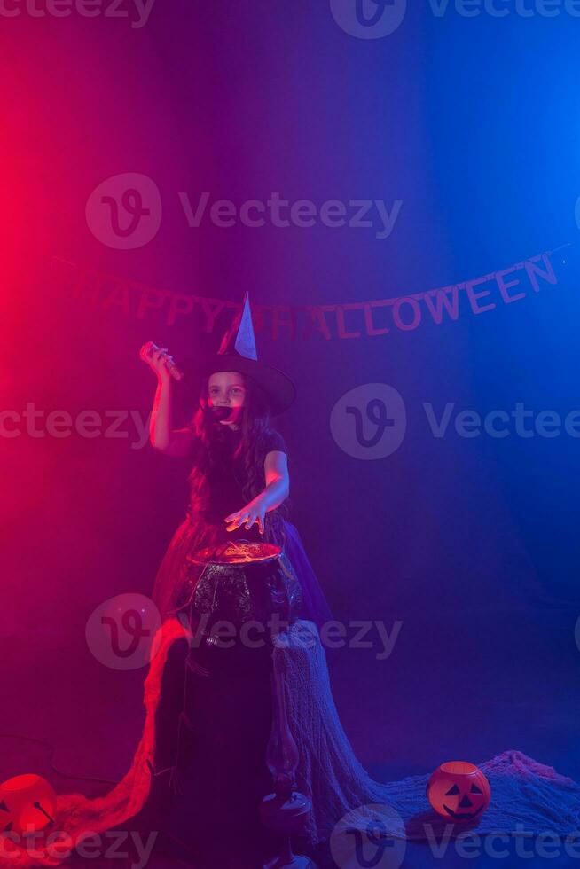 Little witch child cooking potion in the cauldron on Halloween. photo