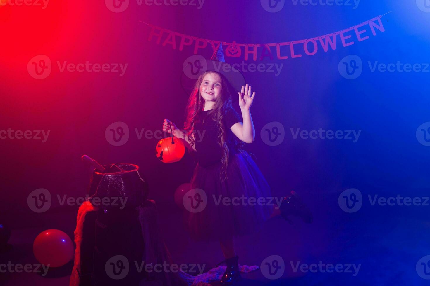 Little girl holds broom on Halloween holiday. Kid girl wear witch costume. Fantasy, fairy tale and masquerade concept. photo