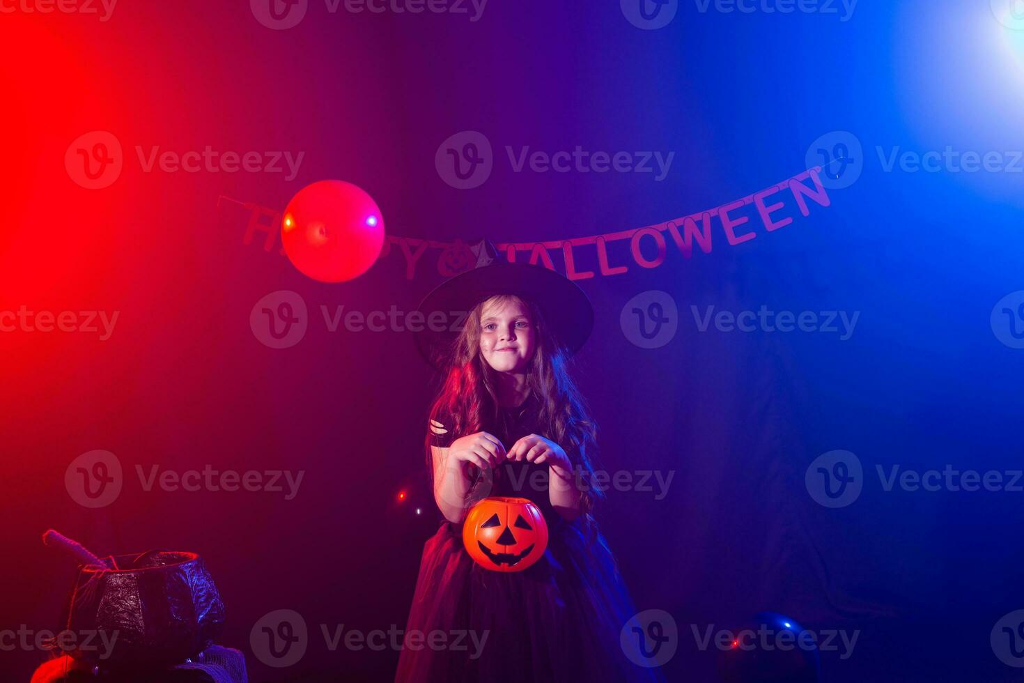 Funny child girl in witch costume for Halloween with pumpkin Jack. photo