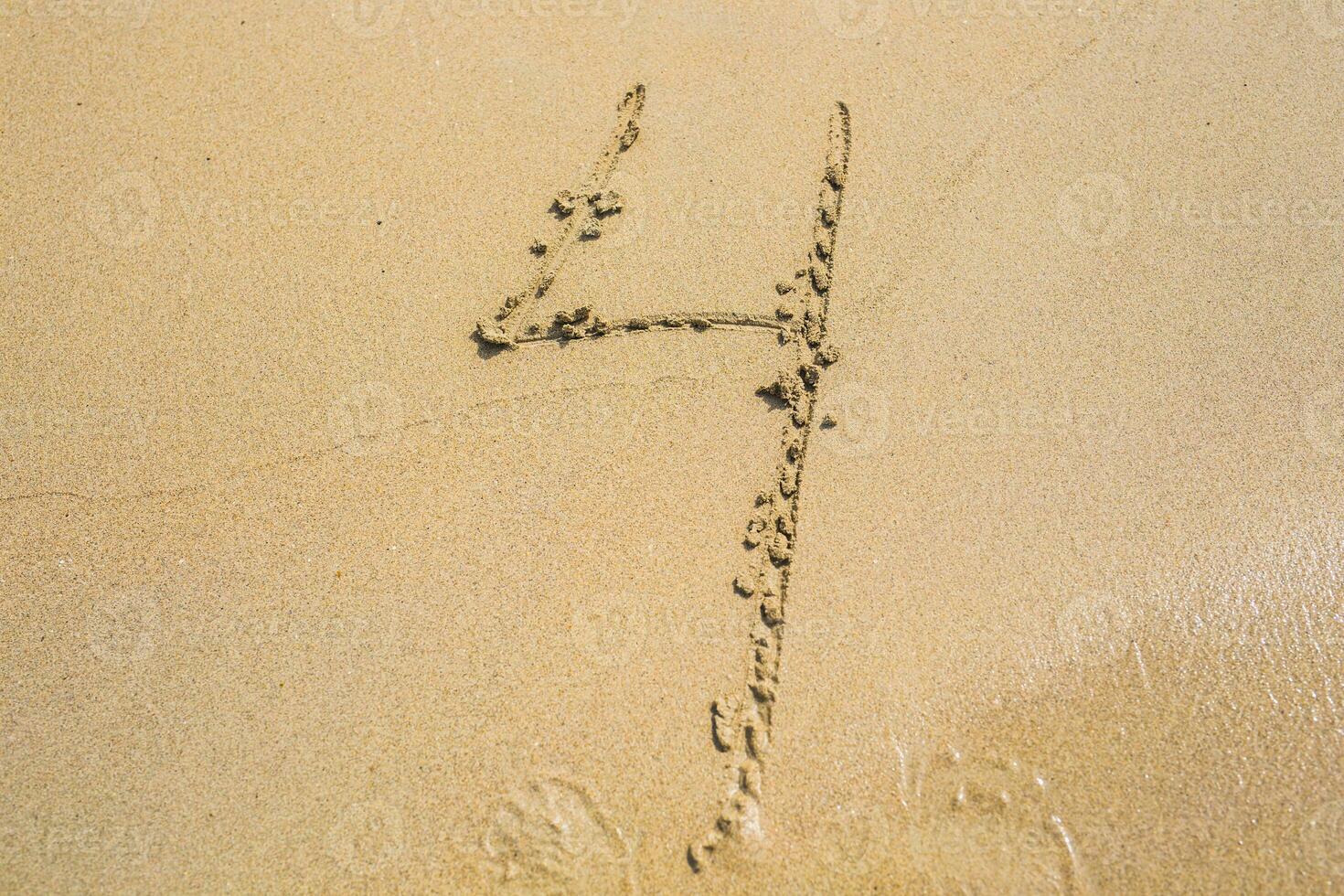 The number four drawn on sand at the beach, holiday concept background photo