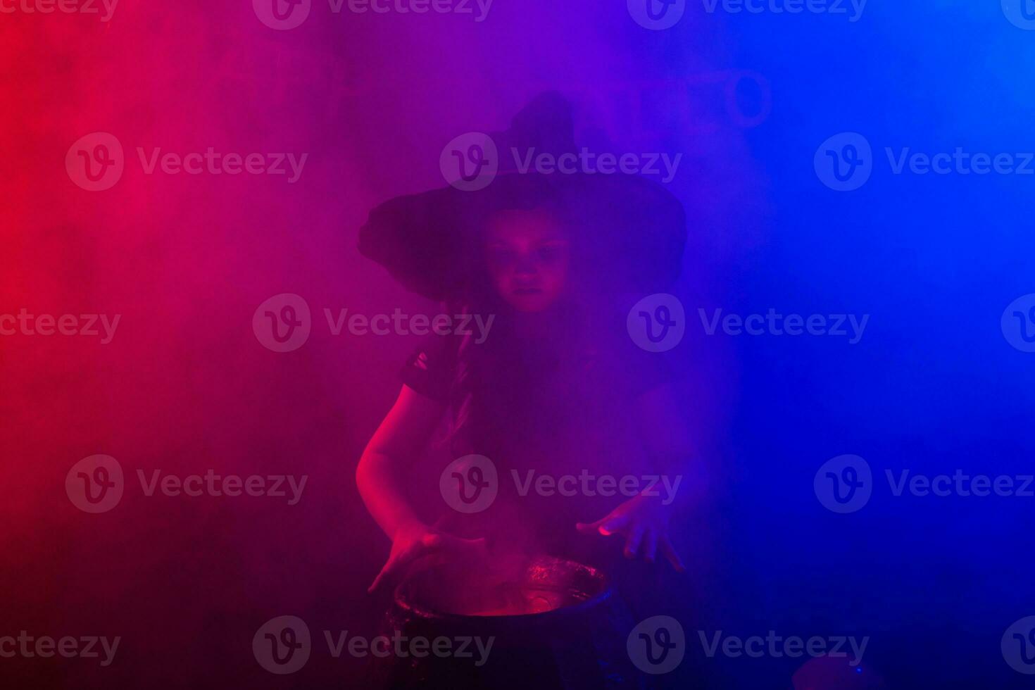 Child girl witch preparing a potion in the cauldron at halloween holidays. Copy space. photo