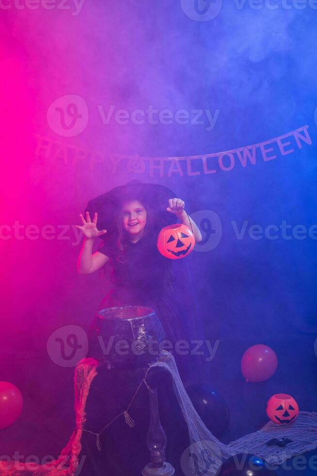 Funny child girl in witch costume for Halloween with pumpkin Jack. photo