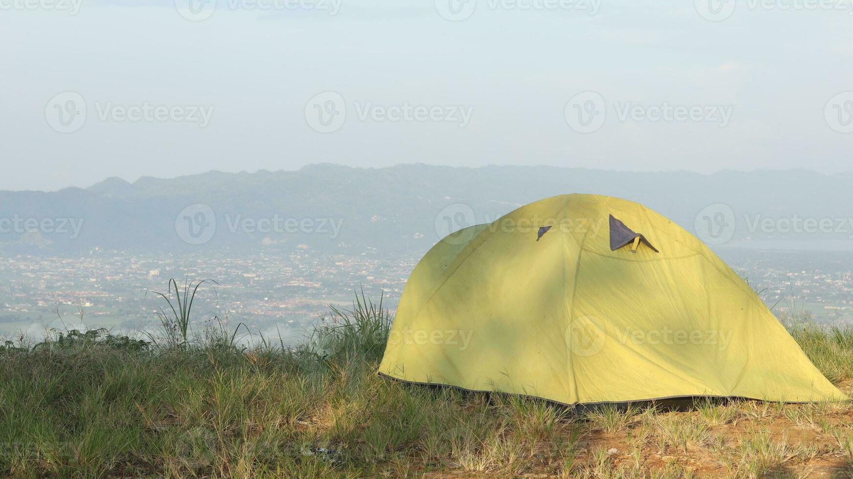 Camping tent on a hill with mountains in the background in the morning photo